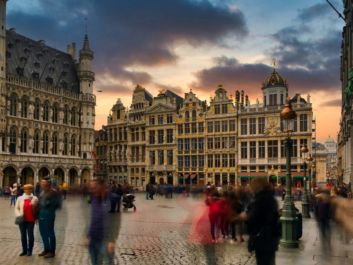 Zicht op de Grote Markt in Brussel bij zonsondergang met historische gebouwen en mensen die wazig lijken te bewegen
